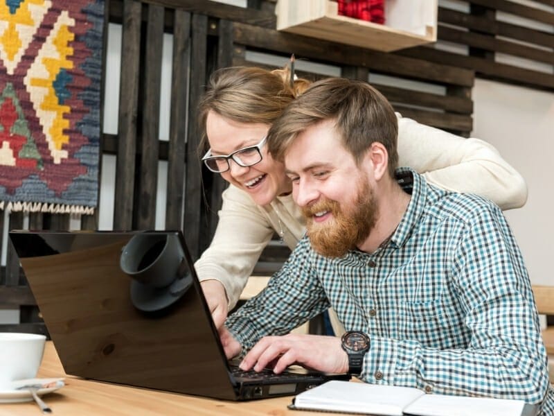 picture of happy customers looking at a website on a laptop. Successful web design