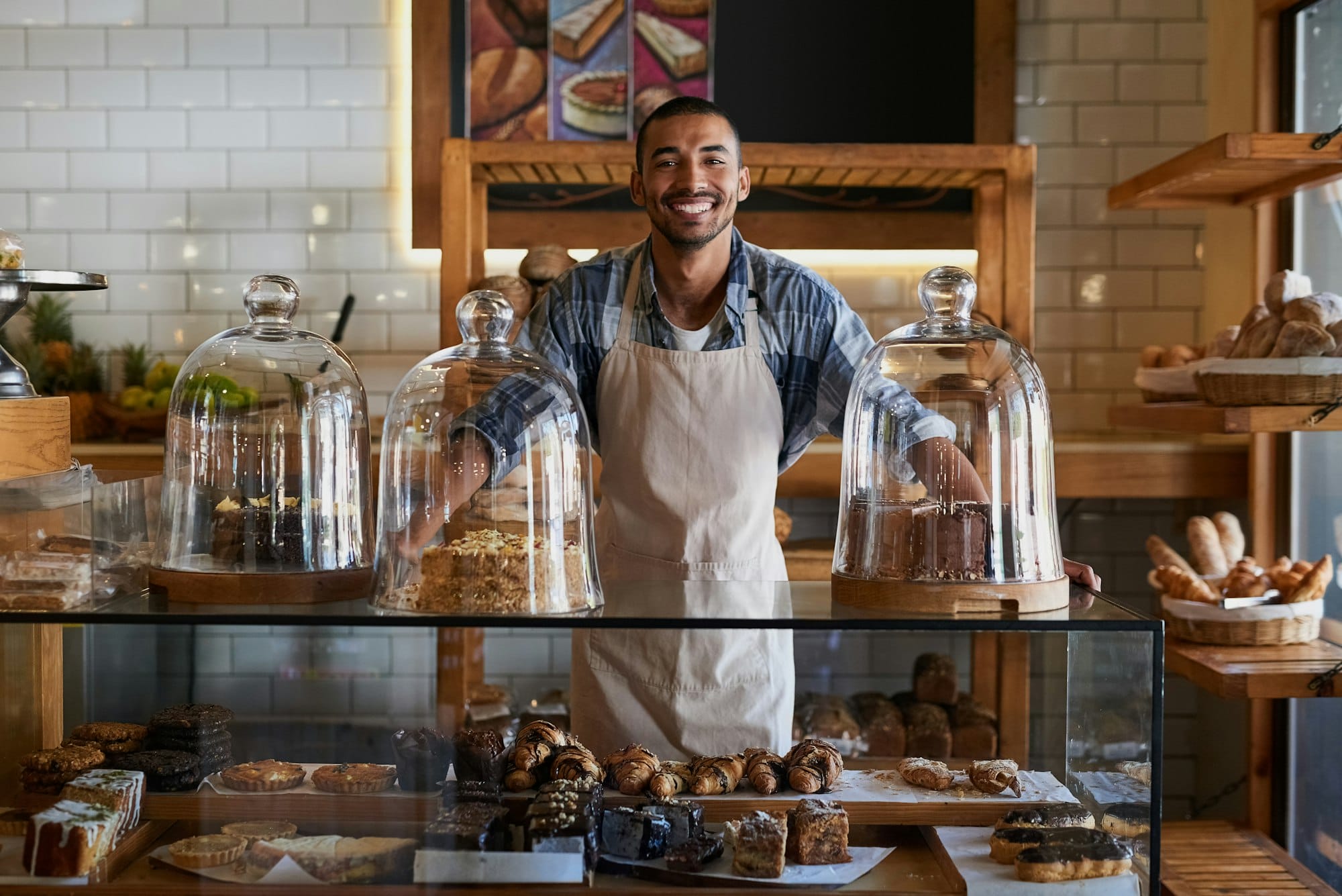 Portrait of a young business owner standing behind the counter of his bakery