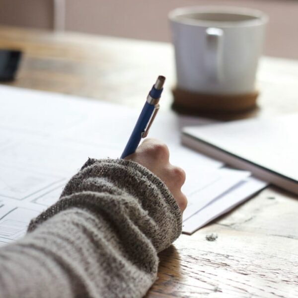 A person writing on a piece of paper at a desk.